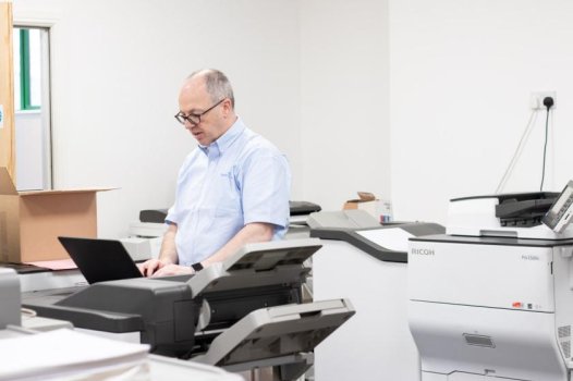 man using laptop near printers