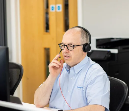 man using computer whilst taking call via headset