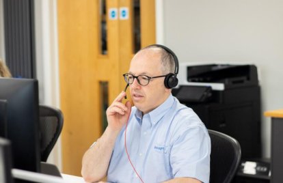man using laptop whilst taking call via headset