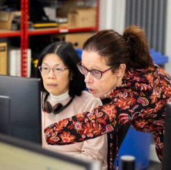 two women pointing at computer screen