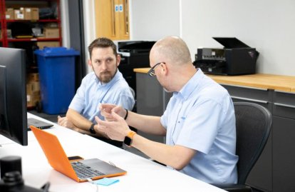 two men talking at desk